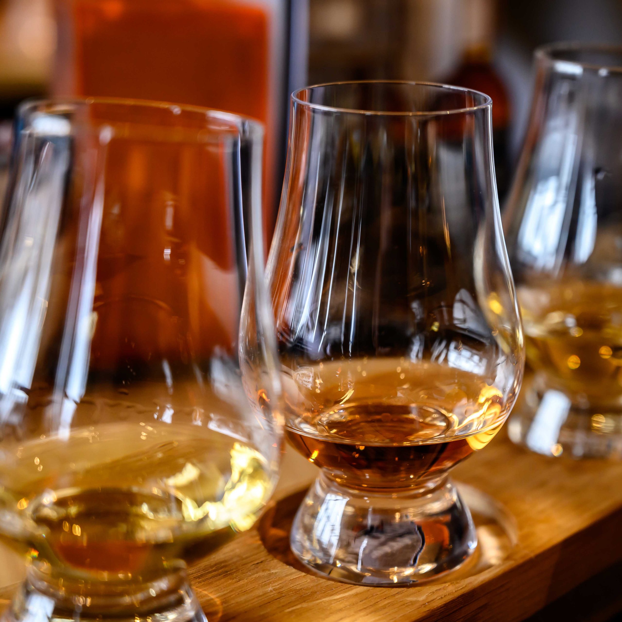 line up of low glasses with whiskey